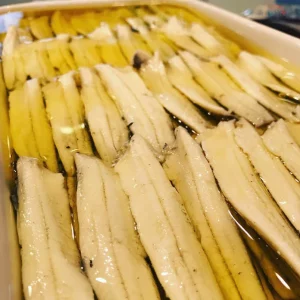 Boquerones de Blanes en vinagre y aceite de oliva sobre plato blanco.
